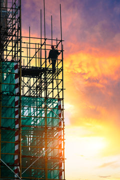 workers and construction site at sunset