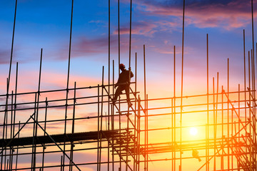 workers and construction site at sunset