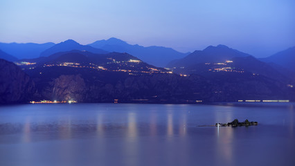 Gardasee am Abend, die kleinen Insel Trimellone  und Bergen im Hintergrund. 
