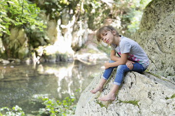 Girl sitting on a rock next to the Waterfall of the bucket in the Selva de Irati in Navarra, Spain.