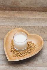 Glass with soy milk and soy bean on wooden heart shape plate