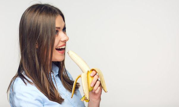 Smiling woman eating peeled banana.