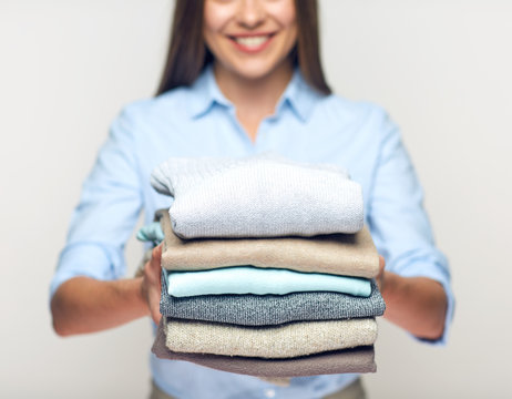 Woman holding stack of folded clothes.