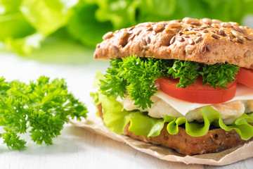 Homemade sandwich with chicken, fresh vegetables and herbs. Close-up.