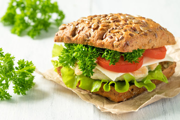 Homemade sandwich with chicken, fresh vegetables and herbs. Close-up.