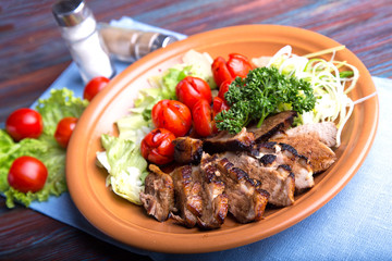 Pieces of roasted meat with vegetables. Grilled meat with tomatoes and spices
