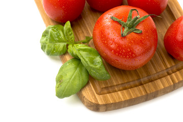 Tomatoes with basil on a cutting board on a wooden background