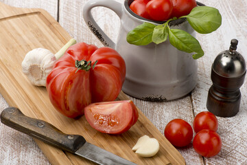 Tomatoes and garlic basil on a cutting board on a wooden background