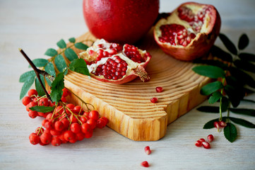 Fresh juicy pomegranate on a light background. On the wooden end of it. Next brush the ash. Healthy eating. Vegetarianism