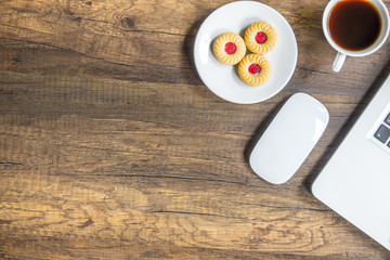 Top view home office table with laptop, coffee and cookie on wooden table. Modern office top view at home. New life style. Concept : business and office.