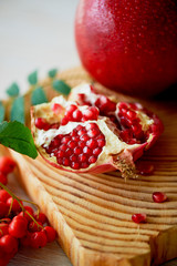 Fresh juicy pomegranate on a light background. On the wooden end of it. Next brush the ash. Healthy eating. Vegetarianism