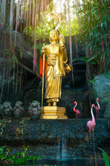 Golden buddha, statues of monkeys and pink flamingo in Asia