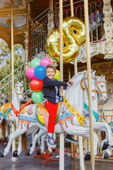Boy with bunch of colorful balloons on the carousel in Paris.