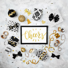 Fototapeta na wymiar Card with word Cheers with black and gold Christmas gifts, bows and decorations. Flat lay, top view.