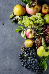 Tuinposter Variety of autumn fruits ripe organic apples, three kind of grapes, pears with leaves over dark texture background. Top view with space © Natasha Breen