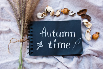 Naklejka premium Text Autumn Time on black paper and fall decor elements. Fall background.