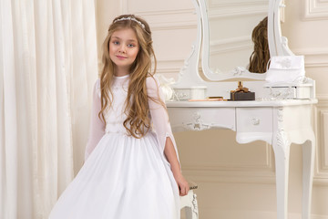 beautiful girl little princess long hair, curly and amazing blue eyes in communion dress and tiara...