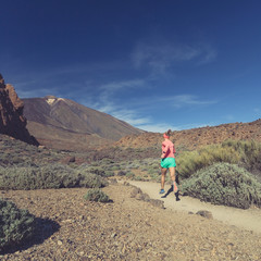 Fototapeta premium Young woman trail running in mountains on sunny day