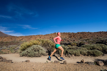 Trail running woman in mountains on sunny day