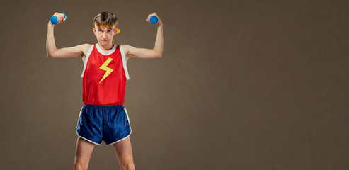 A thin funny guy in sports clothes with small dumbbells