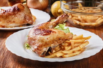 Roasted chicken legs with french fries and lettuce