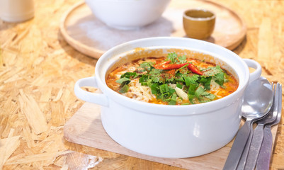 Delicious spicy noodles (Tom Yum) with coriander and vegetables on plywood dining table with copy space