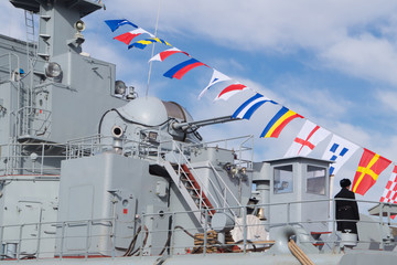 Top part of big military battleship with towers, masts, flags of coloring and antennas