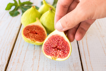 man's hand holding a sliced fig over a wooden table