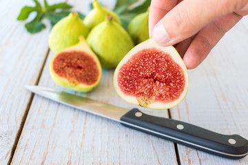 man's hand holding a sliced fig over a wooden table