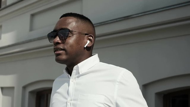 Attractive african american businessman talking on the phone using wireless earphones. A serious man talks. Series of business people - interns, financial advisors, CEO. Close up