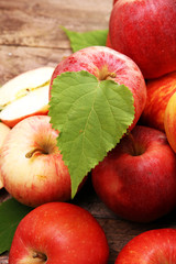 Ripe red apples with leaves on wooden background