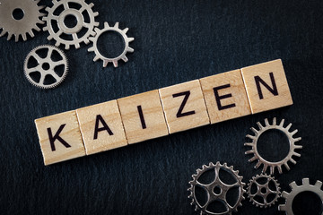 Teamwork in business and the concept of continuous improvement, with tiles spelling Kaizen (meaning...