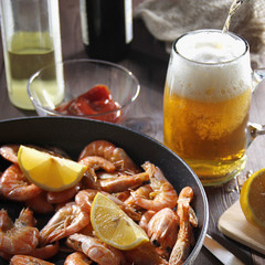 Beer pouring in glass and pan filled with appetizing red shrimps
