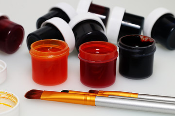 Artist's set: Brush, palette, open and closed jars with multi-colored gouache and covers from them...