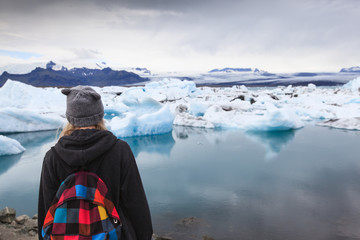 Back view of traveler young girl  with backpack. Glacier lagoon Jokulsarlon, Iceland
