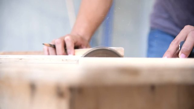 Close up Asian Carpenter using circular saw for cutting wooden planks.