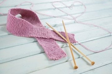 Close-up of woolen Breast Cancer Awareness ribbon with needles
