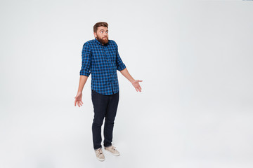 Full length portrait of a confused young bearded man