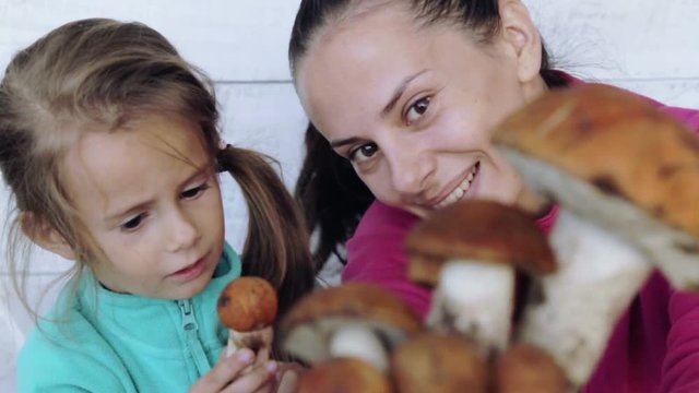 Mom and daughter clean freshly picked mushrooms. Portrait of a mother with her child for cleaning ecologically clean food.
