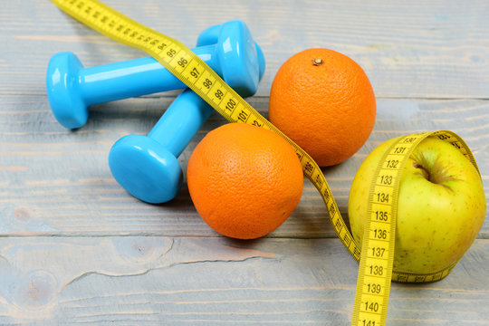 home exercise concept, dumbbells weight with measuring tape and fruit