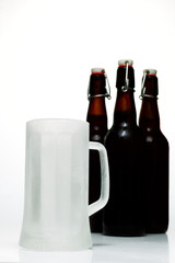 Beer glass with dark beer and two full beer bottles on a white background