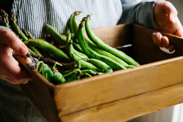 A wooden crate filled with early summer vegetables.