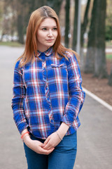 Portrait of a beautiful girl. smiling, posing on camera. in a blue shirt in a cage. Against the background of the autumn park