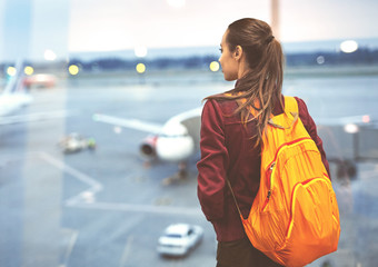Girl at the airport window looking outside