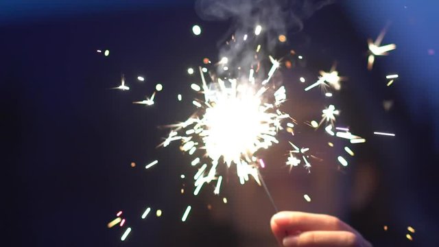 Smiling young girl with sparkler at sunset in slow motion