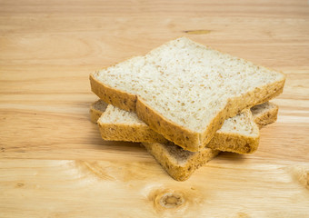 Three slice whole wheat bread stacked on wooden table