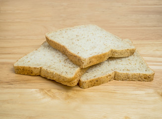 Three slice whole wheat bread stacked on wooden table
