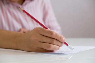 Closeup of woman's hand writing on paper. Close up of lady's hand writing in notepad placed on desktop with other items. girl's hand with a pencil and paper at the table.