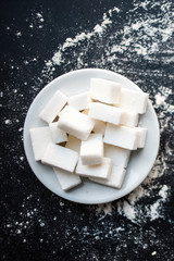 Unhealthy food concept - sugar  and flour on a black background. Dangerous high amount of sugar in food. Carbohydrates sources, top view.