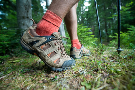 legs of the traveler in hiking boots with trekking poles